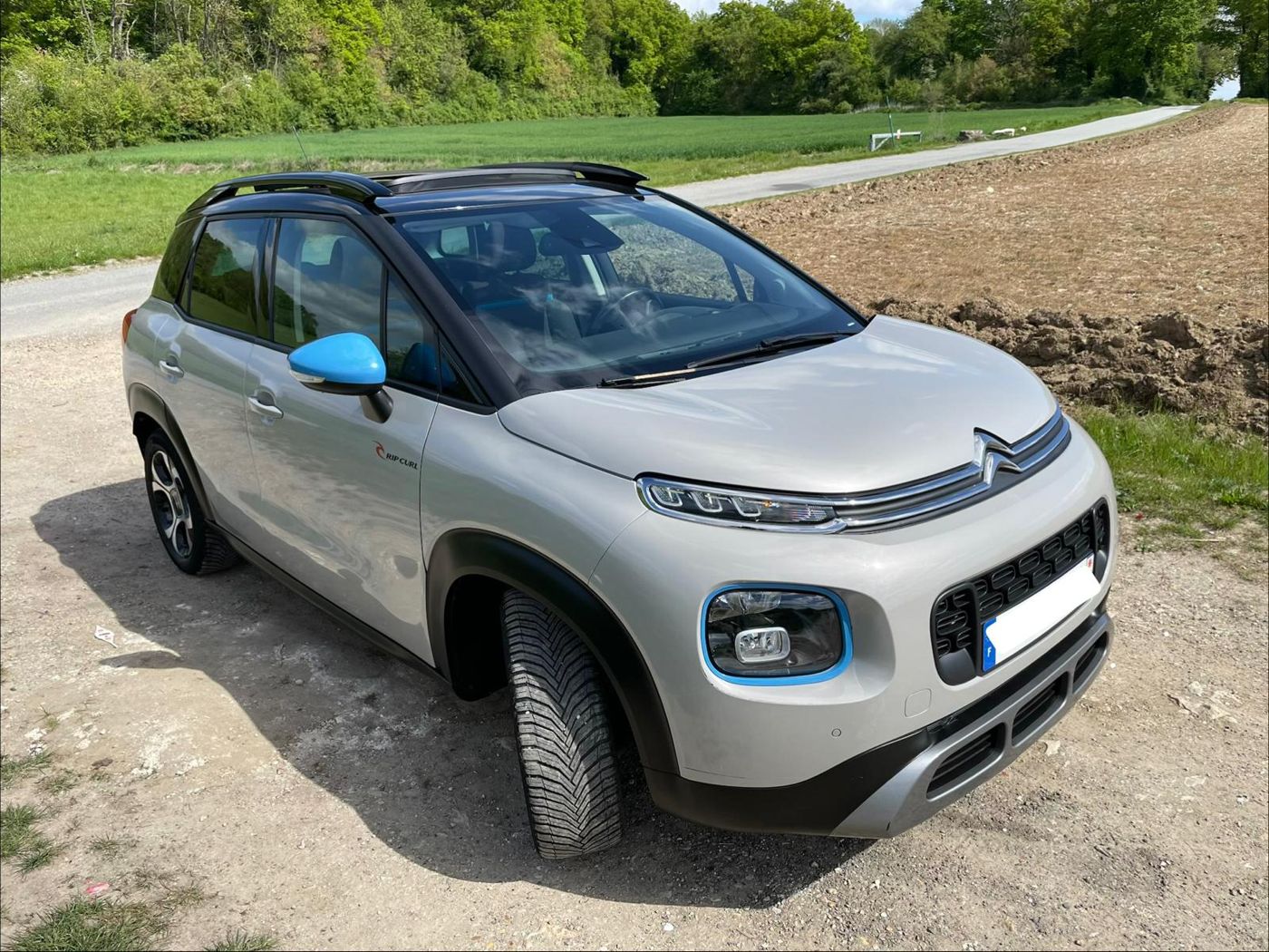 Citroën C3 Aircross Rip Curl, blanche au toit noir, sur un chemin de campagne